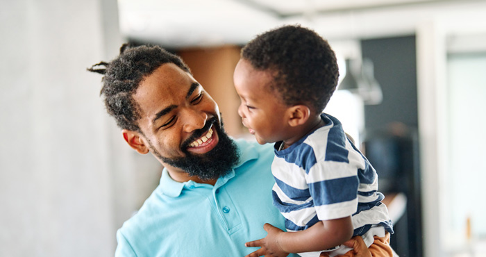 Photo: Father smiling while holding his son.