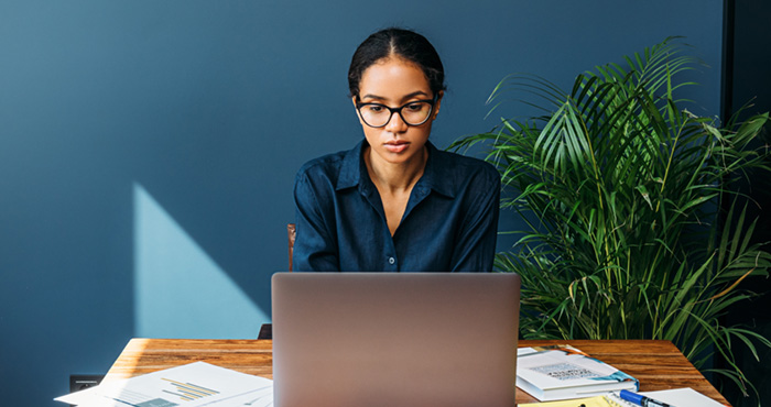 Photo: Woman wearing glasses and looking at a laptop screen.